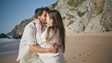 Joyful future parents kissing spinning on sandy beach close up. Pregnant spouses