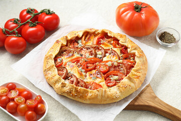 Tasty galette with tomato and cheese (Caprese galette) on light textured table, closeup