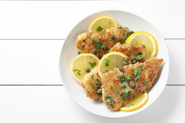Delicious chicken piccata on white wooden table, top view
