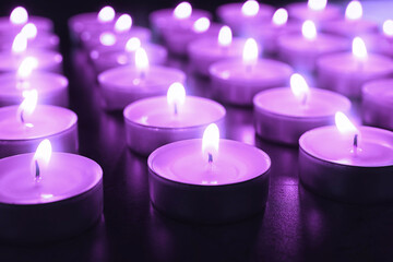 Obraz na płótnie Canvas Beautiful burning violet candles on black background, closeup. Funeral attributes