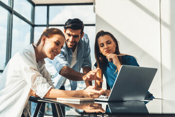 Group of diverse profession business people pointing at laptop displayed idea. Portrait of business team show marketing strategy present by laptop with statistic document scatter on table. Tracery.