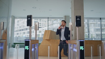 Business man open turnstile waving to face id screen at modern business center.