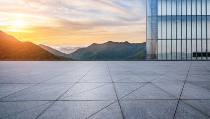 Empty square floor and glass wall with green mountain nature landscape at sunrise