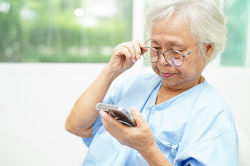 Asian senior woman wearing eyeglasses or vision glasses using a smartphone at home care service.
