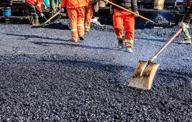 Teamwork, Workers laying asphalt road at construction site.