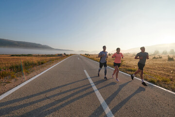 Fototapeta premium A group of friends, athletes, and joggers embrace the early morning hours as they run through the misty dawn, energized by the rising sun and surrounded by the tranquil beauty of nature
