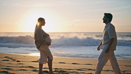 Pregnant couple hugging sunset feeling happiness. Expectant parents at sundown