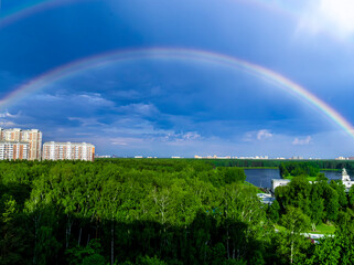 Rainbow over forest and calm lake water in Moscow. general plan