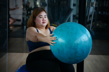 Naklejka premium Sporty woman exercising on ball fitness workout and health concept. Training working out and sitting on gymnestic fitball at gym.