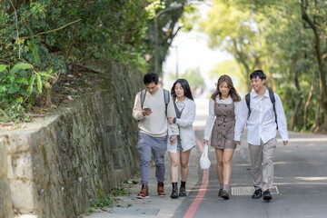 Scenery of four Taiwanese college students walking while talking in the nature of the Maokong, a tourist attraction in Wenshan District, Taipei City, Taiwan 台湾台北市文山区の観光名所の猫空の自然の中を台湾人の大学生の男女四人が話しながら歩く風