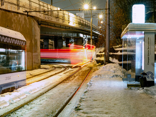 the tram leaves the stop in night city, motion blur view
