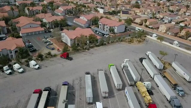 Aerial flyover of Semi Truck parking lot, apartment complex and residential neighborhood with freeway at end