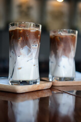 Two iced Mocha coffee two layers fresh milk and espresso short on wooden table at cafe. Refreshing summer drink concept, selective focus