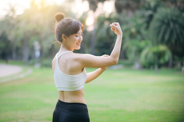 Strong fitness asian woman runner showing off muscular arms flexing biceps. wellbeing success concept.