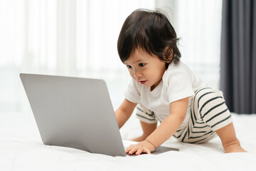 toddler baby typing on laptop computer on bed