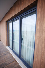 Fototapeta premium Modern front window with thin curtains and house walls from the outside view.