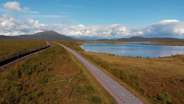 Aerial: ore train in Kiruna, Sweden by a main and deserted road among forests and lakes