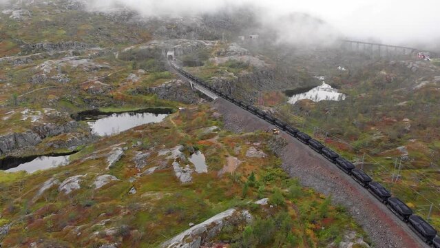 Aerial: ore train in S&oslash;sterbekk stasjon, close to the border between Sweden and Norway in north Lapland entering a tunnel