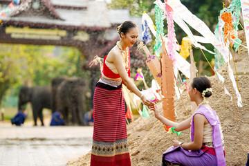 Beautiful Thai young lady ware Thai traditional dress give a small paper flags to her friends to...