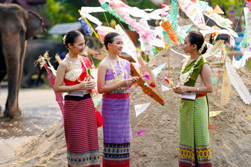 Beautiful Thai young lady ware Thai traditional dress stand and chatting on pile of sand in temple...