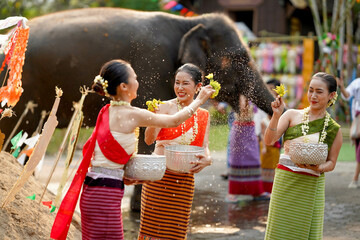 Closeup beautiful Thai young lady ware Thai traditional dress use flowers to sprinkle water on each...