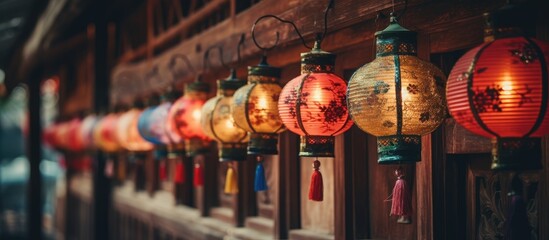 A row of vibrant lanterns adorns the wooden wall at a public event, creating a colorful and...