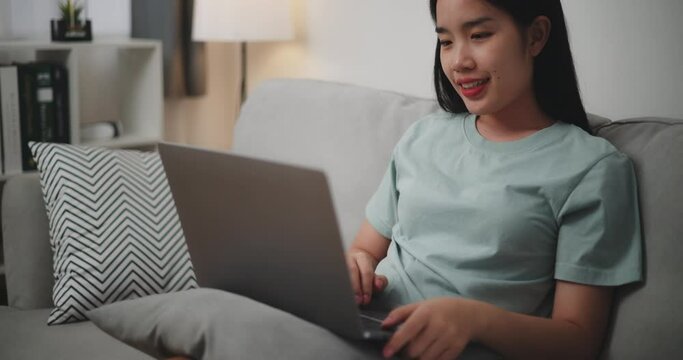 Footage dolly shot, Happy young woman sitting on sofa using laptop for online shopping cashless in living room at home ,Internet Connectivity and Online Concept.
