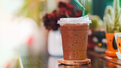 Iced coffee in a plastic glass on a wooden table. Copy space.