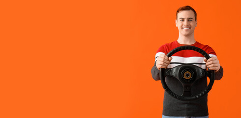 Young man with steering wheel on orange background