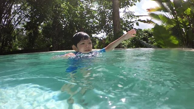 cute boy swimming into the pool, surface of water with sunlight