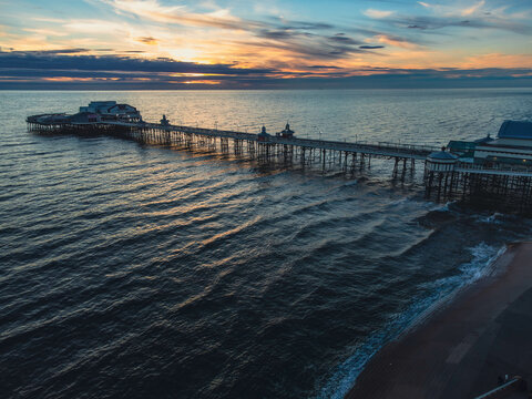 Aerial view of a pier at sunset. Sea or ocean waves around the pier