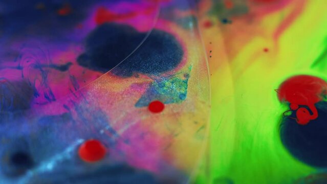 Oil fluid. Paint bubbles. Defocused vivid pink blue green red color glitter transparent texture gel blob floating ink water mix abstract art background.