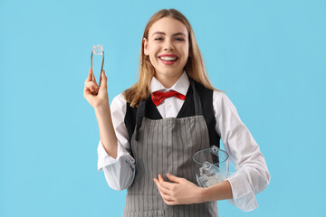 Female bartender with ice cubes on blue background