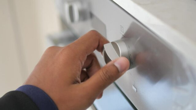 Close up of men hand setting temperature control on oven.