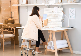 Female jewelry designer working with laptop in office