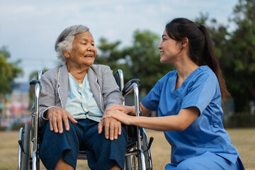 Obraz premium happy nurse take care and talking with senior woman patient in wheelchair at park, friendly caregiver