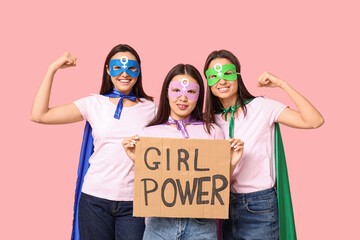 Women in superhero costumes holding cardboard with text GIRL POWER on pink background