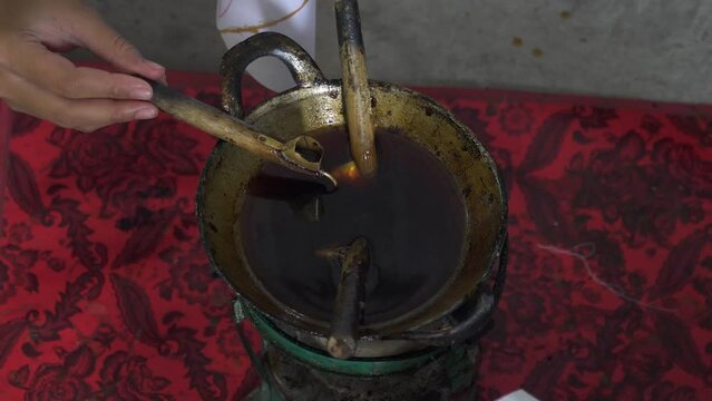 4k footage of participants learning to make traditional batik using hot wax in a pan and canting drawn on a piece of white cloth. The process of beginners learning to paint traditional Javanese batik