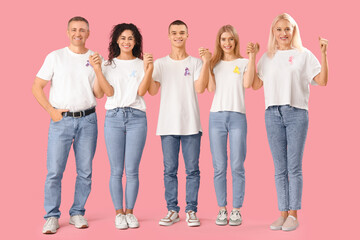 People with different awareness ribbons holding hands on pink background. World Cancer Day