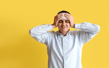 Young man with brain concussion and bandaged head on yellow background