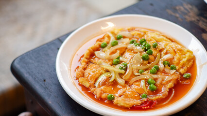 Chinese omelet with sweet sour sauce. Fu yung hai or chinese styles of omelete, served on white plate. Breakfast table situations.