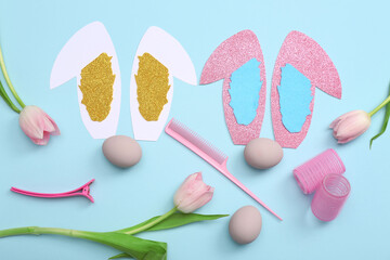 Hairdressing accessories with Easter eggs, paper bunny ears and tulips on blue background