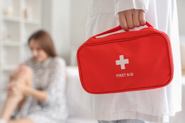 Doctor with first aid kit in bedroom of traumatized woman, closeup