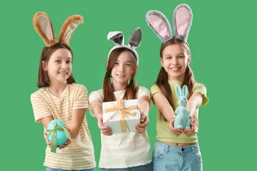 Fotobehang Cute little girl with Easter bunny ears, gift, egg and toy rabbit on green background © Pixel-Shot