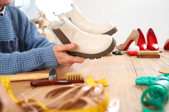 Male shoemaker with boots at table in workshop, closeup © Pixel-Shot