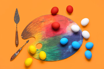 Easter eggs and paint palette on color background. Easter concept.