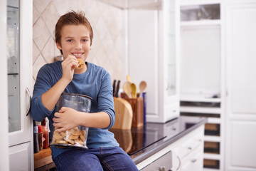 Eating, cookies and portrait of child in home with glass, container or happy with jar of sweets on kitchen counter. House, snack and craving taste of sugar from addiction to unhealthy food or biscuit