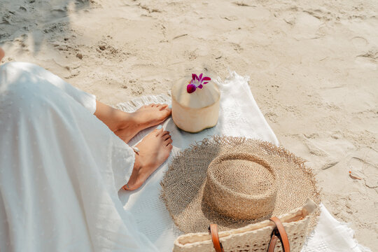 Summer vacation concept Feet and straw hat with coconuts on the sand at the beach