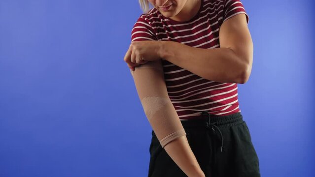 woman wearing an elbow support brace on a blue background, copy space trauma and healing concept