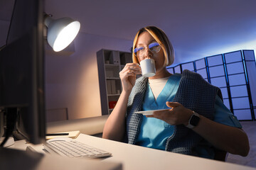 Female nurse drinking coffee at hospital in evening